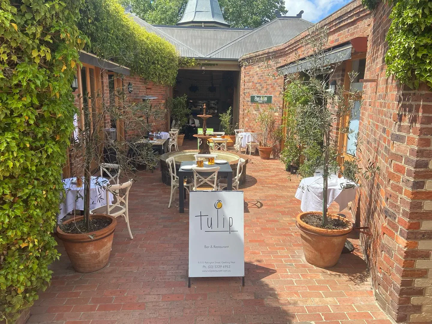 Outdoor dining at Tulip restaurant in Geelong with brick walls and potted plants.