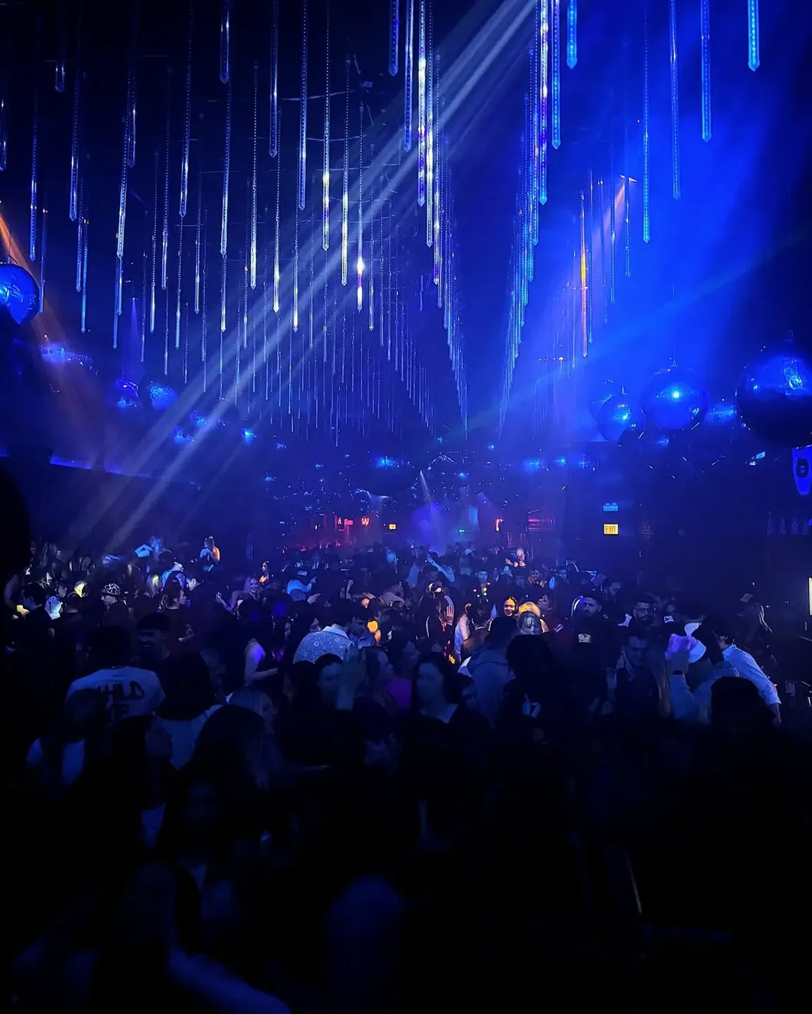 Tunnel nightclub in Chicago, illuminated with blue lights, packed with people dancing.