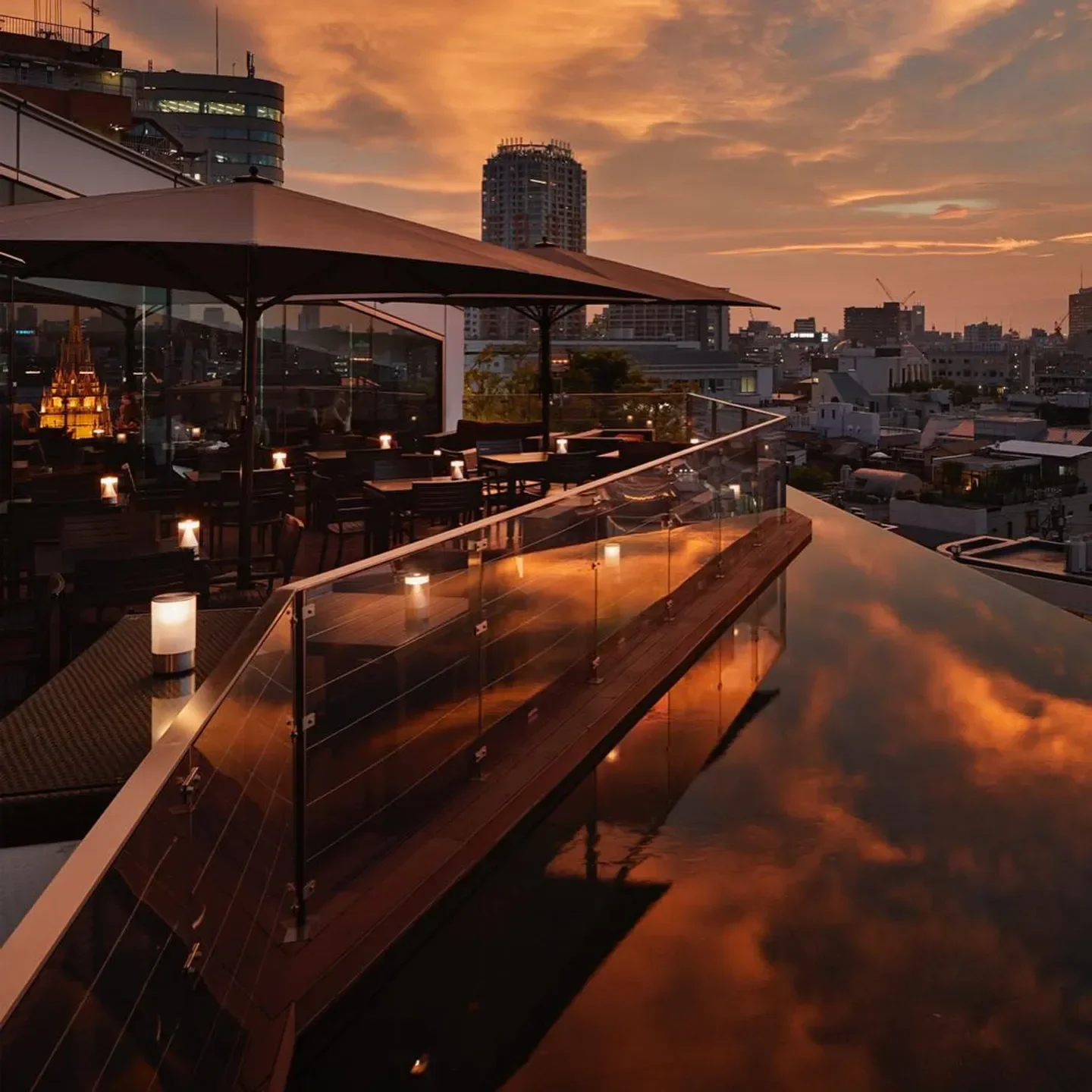 Rooftop view at Two Rooms Grill in Tokyo at sunset, with city skyline reflection