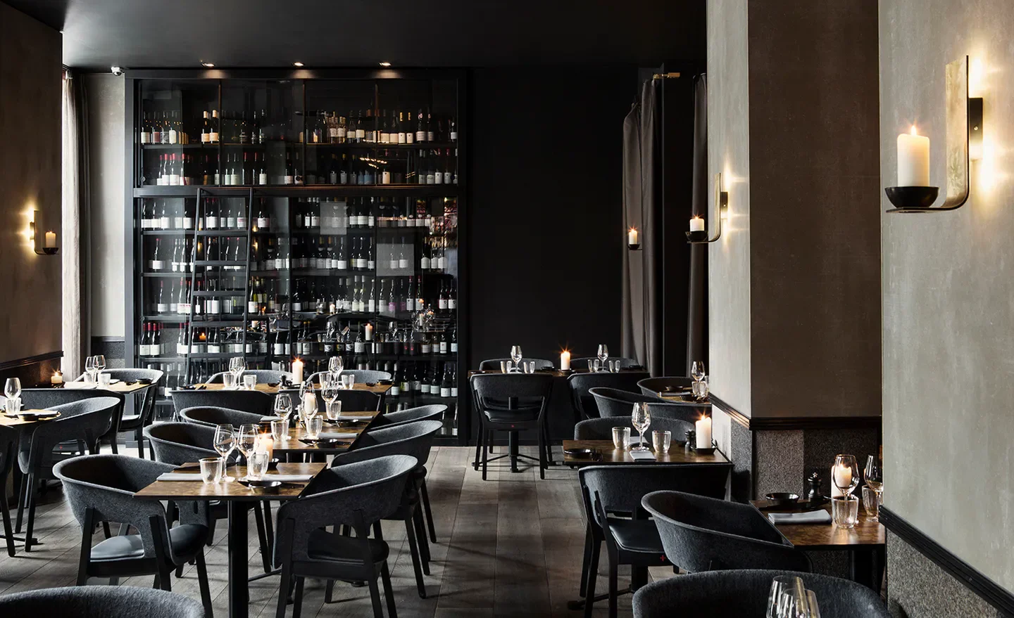 Interior of Uformel restaurant in Copenhagen, featuring a wine display and candlelit tables.