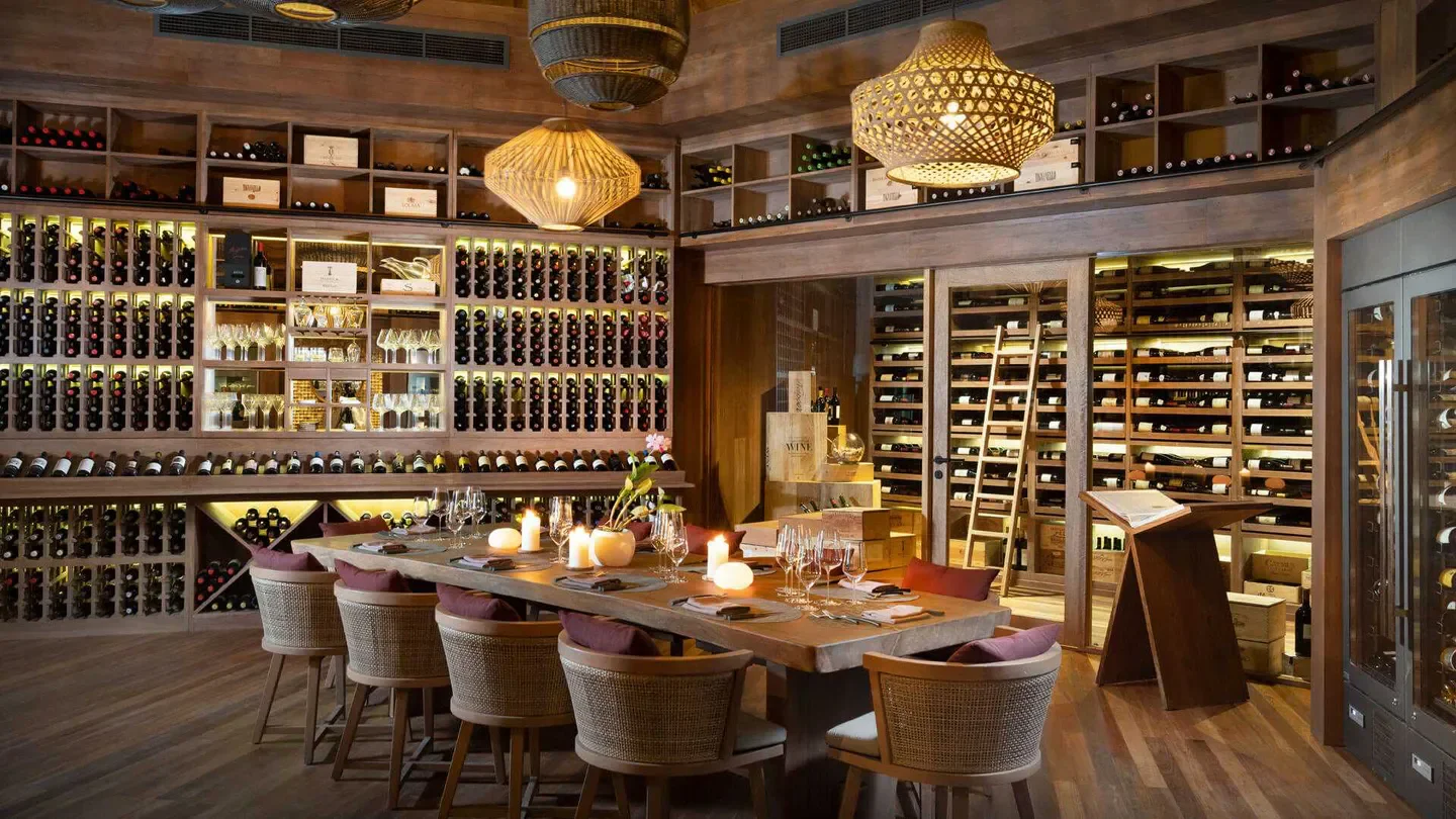 Elegant dining at Vakkaru Reserve in the Maldives, with extensive wine cellar backdrop.