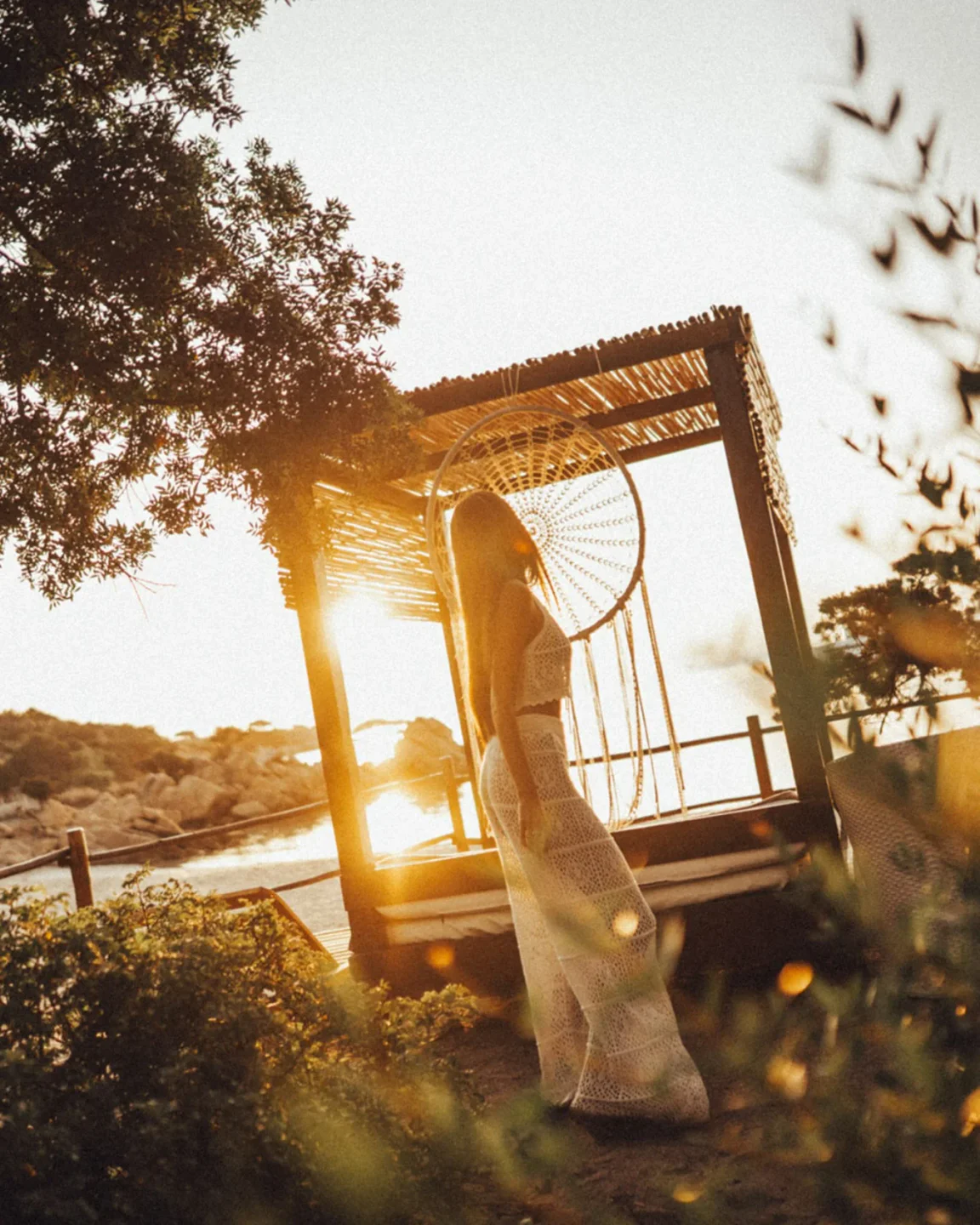 Woman in white attire enjoys sunset ambiance at Vesper Beach Club, Porto Cervo.