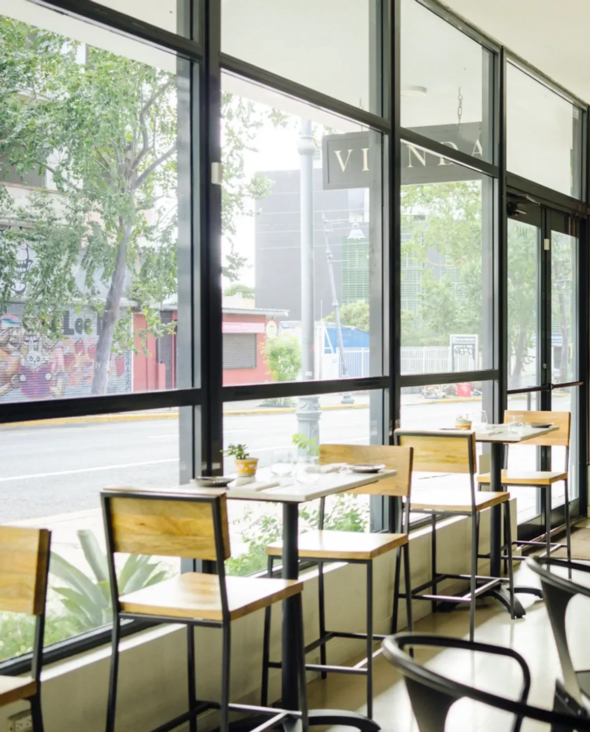 Interior of Vianda restaurant in San Juan, showcasing tables with a street view