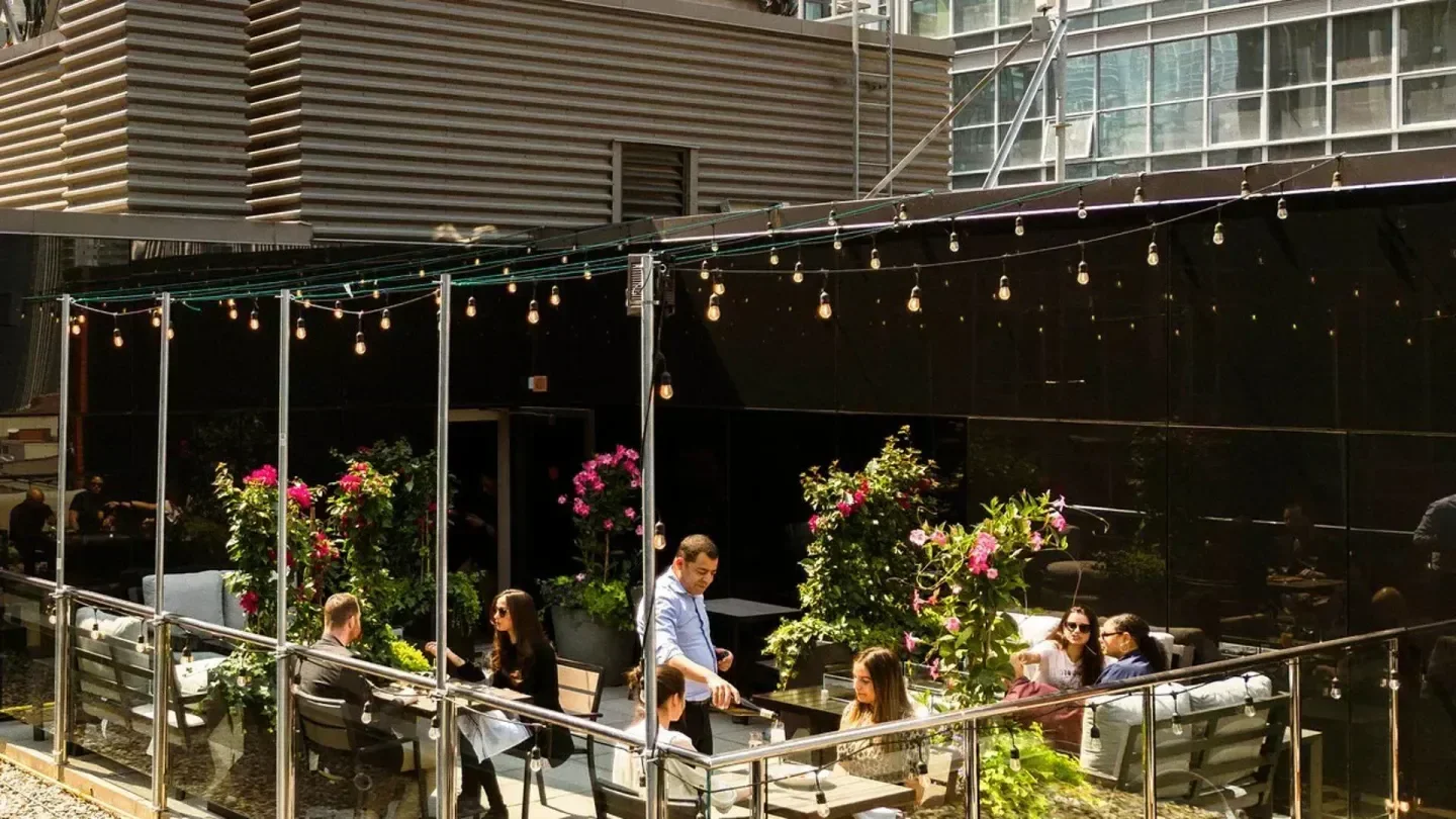Rooftop dining at Victor Rooftop in Toronto with string lights and lush greenery