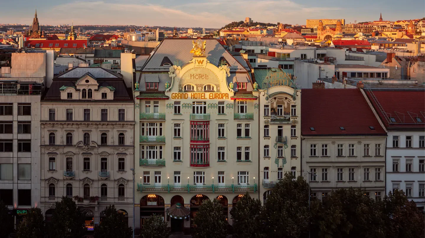 Exterior view of the W Prague hotel, showcasing architecture against Prague skyline at sunset.