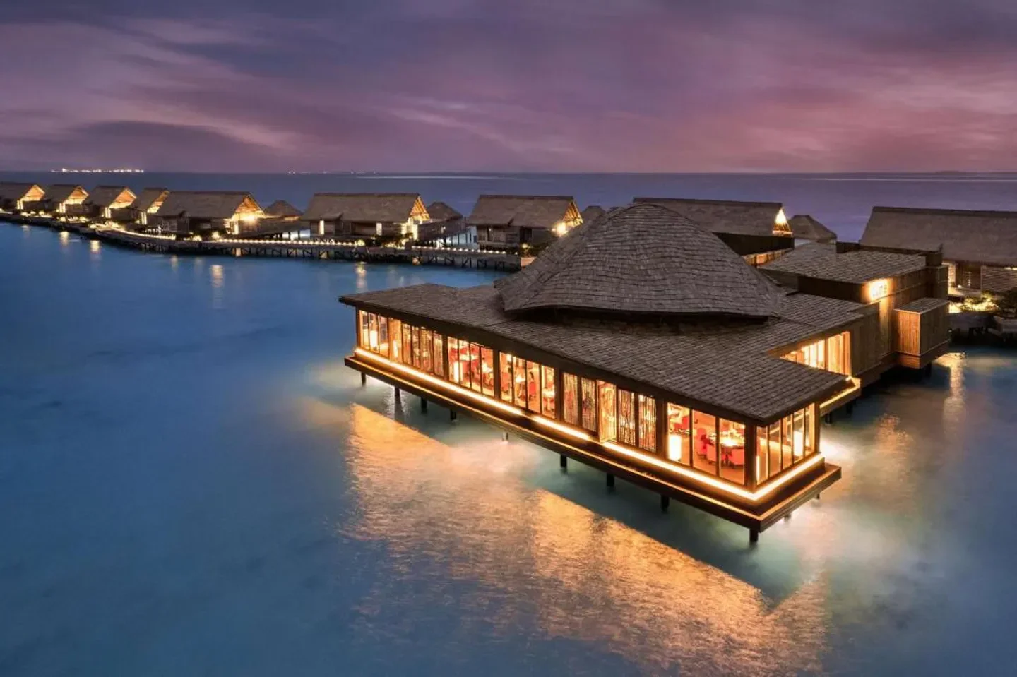 Luxury overwater dining at Waldorf Astoria Maldives Ithaafushi in the Maldives at dusk