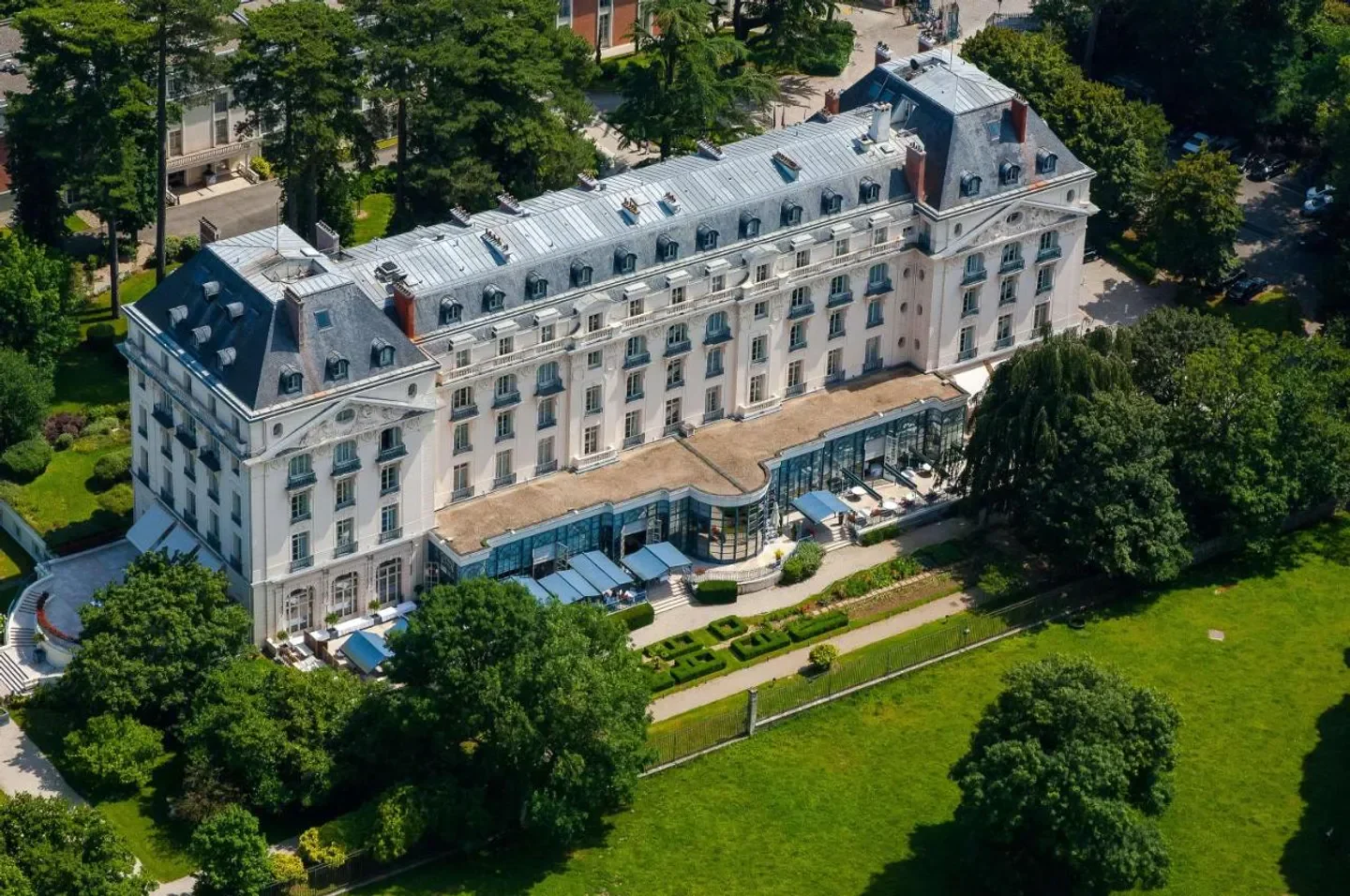 Aerial view of the Waldorf Astoria Versailles – Trianon Palace in Paris, surrounded by lush gardens.