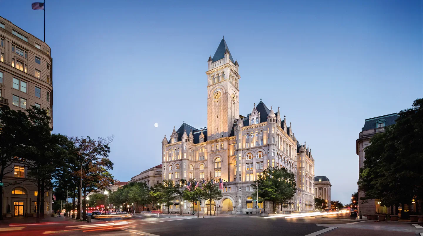 Waldorf Astoria Washington DC lit up at dusk in Washington, DC, with clock tower.