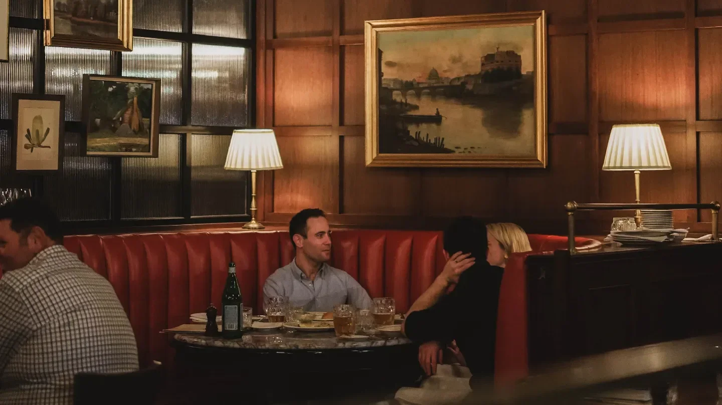 Cozy dining at Walter's Steakhouse in Brisbane, featuring red booths and vintage artwork.