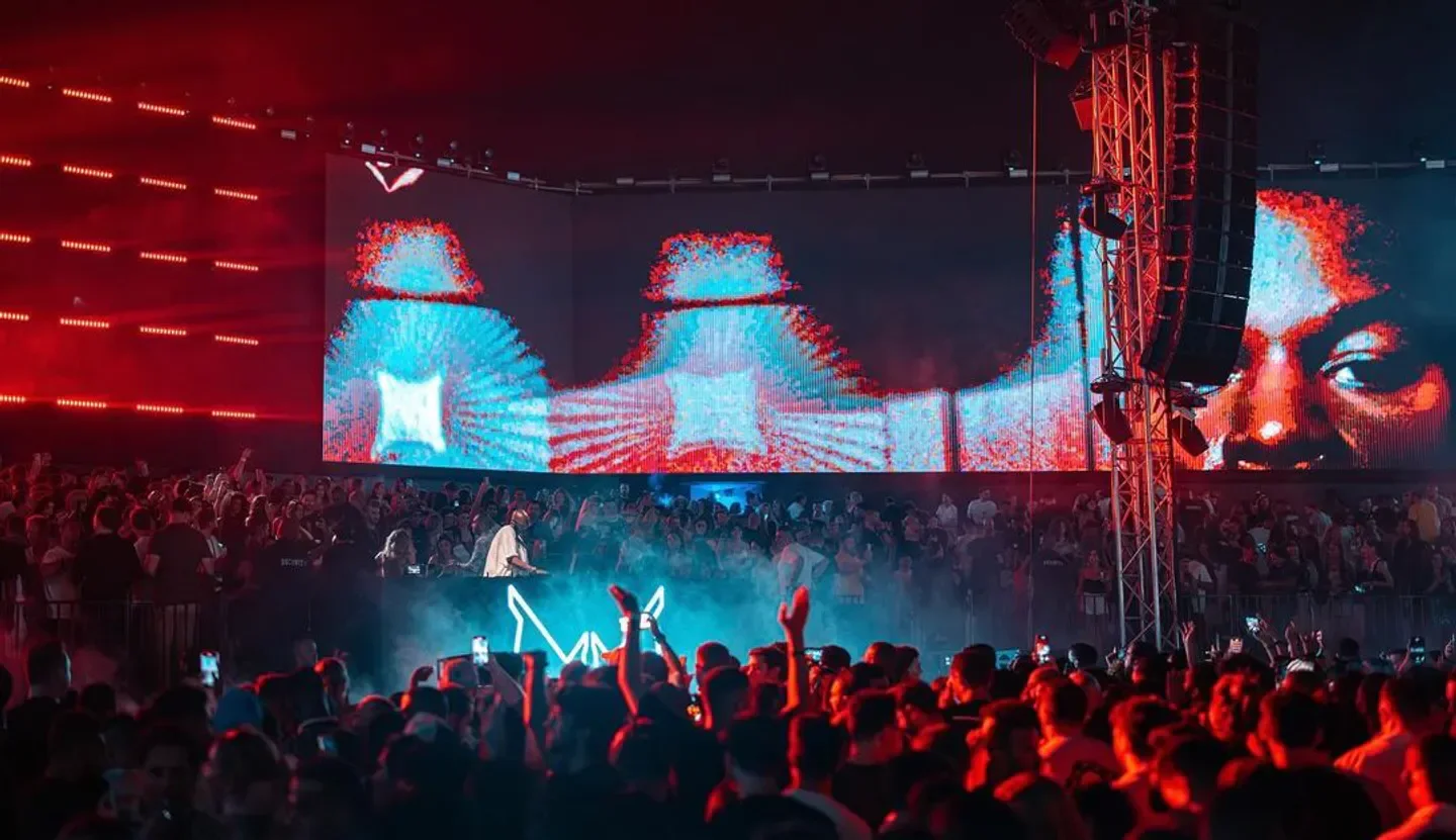 Energetic crowd at White Club Dubai enjoying a live DJ performance with vibrant visuals.