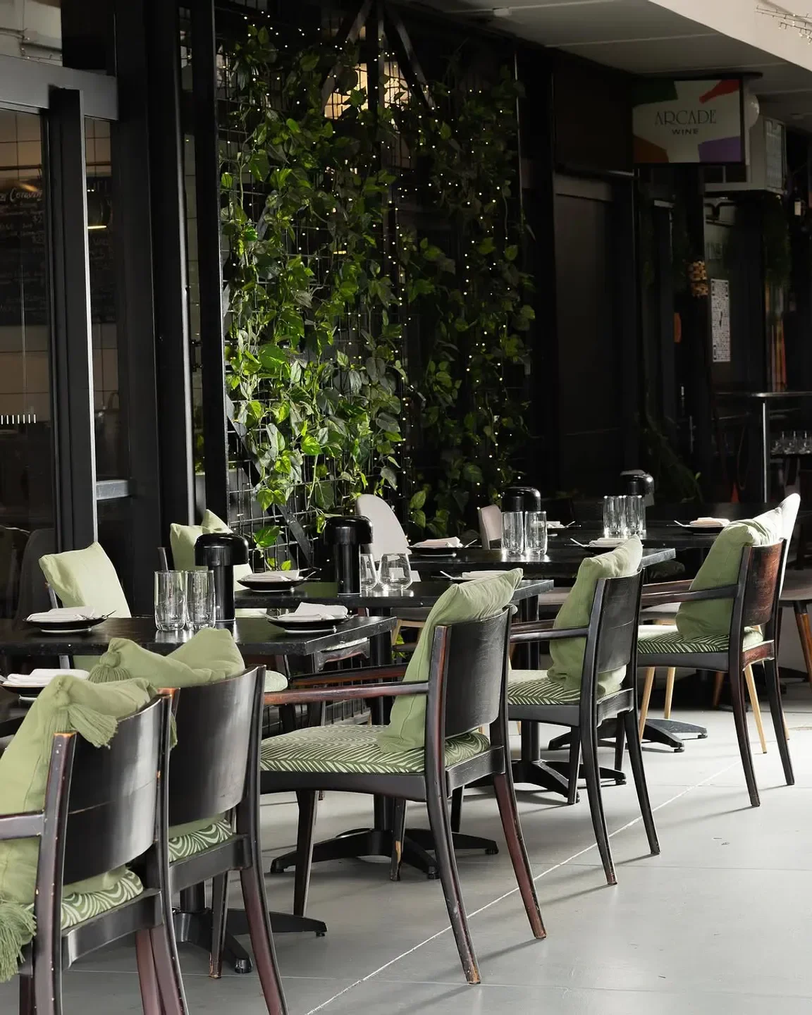 Elegant dining at Wine & Larder in Brisbane, featuring stylish chairs and greenery.