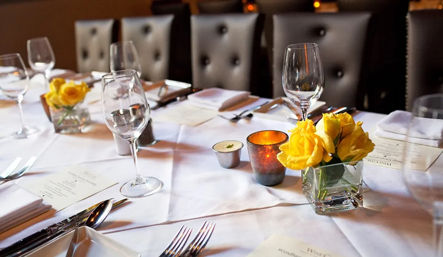 Elegant table setting at Wine Cask restaurant in Santa Barbara, featuring flowers and candles.