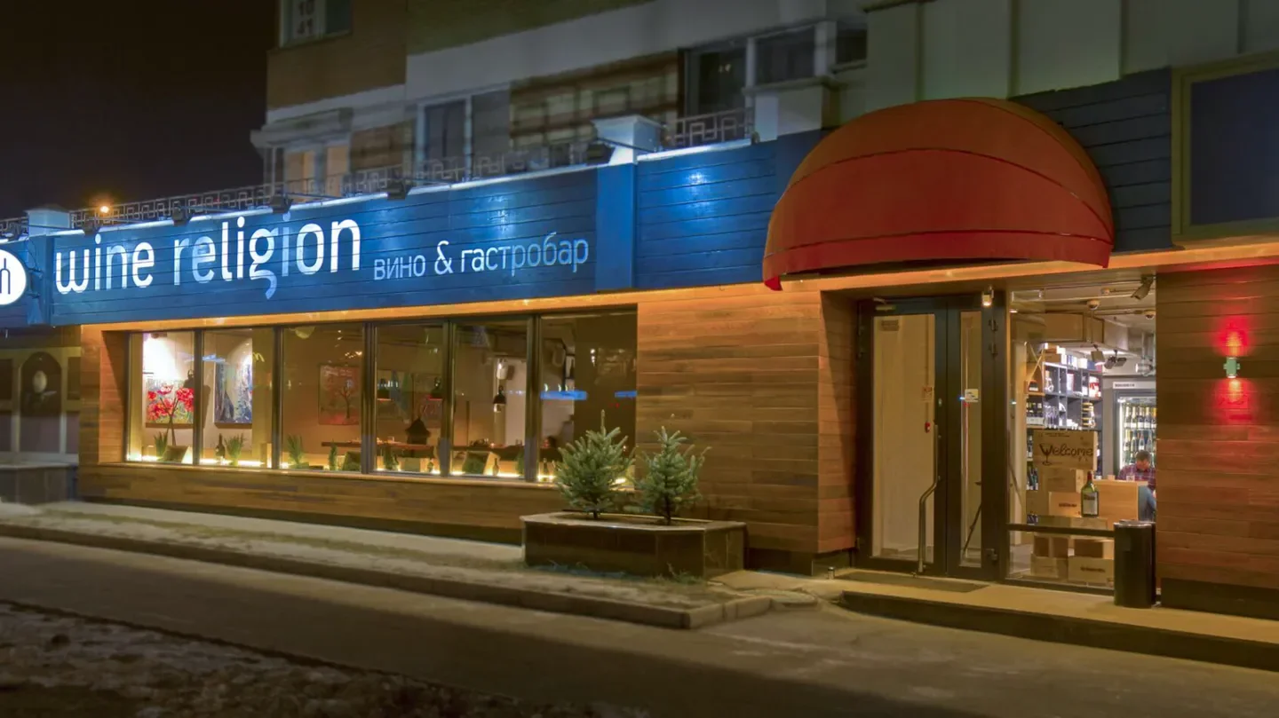 Exterior view of Wine Religion restaurant in Moscow at night, with illuminated sign