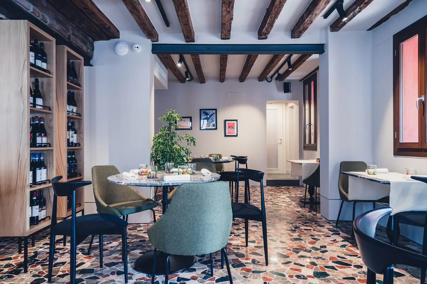 Interior of Wistèria restaurant in Venice, featuring tables, chairs, and wine display.
