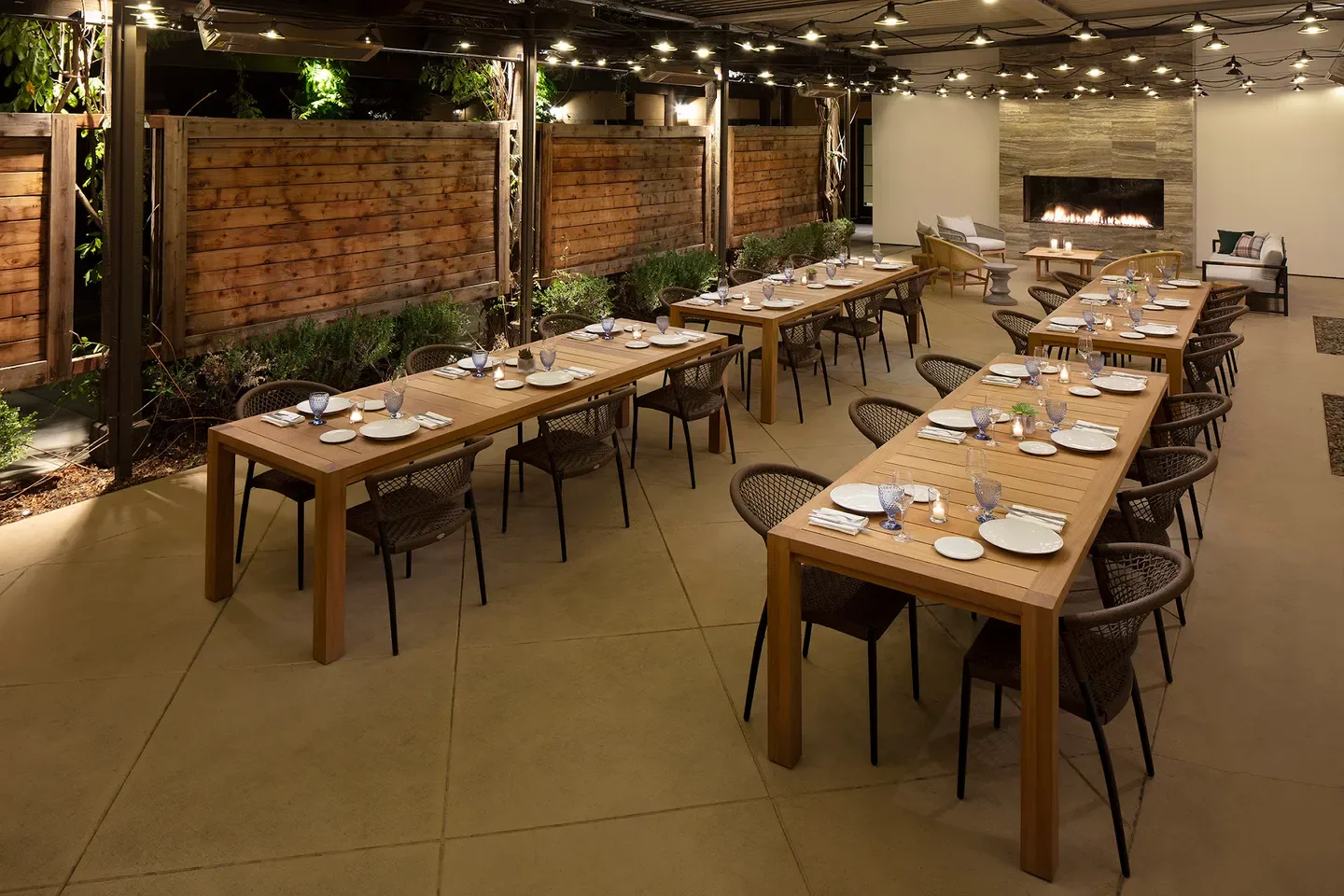 Outdoor dining area at Wit & Wisdom in Sonoma, featuring wood tables and fireplace.