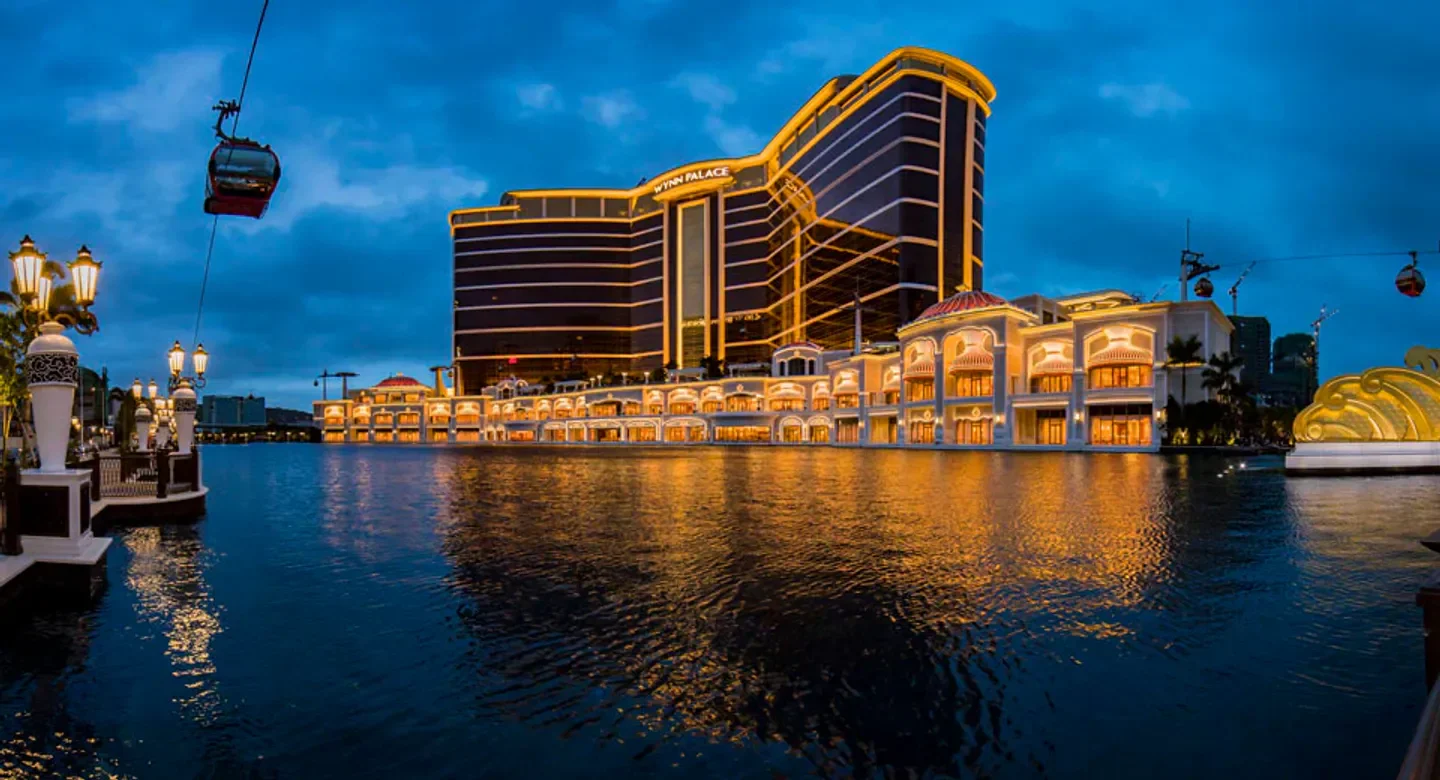 Wynn Palace Macau hotel at dusk with water reflection and cable car