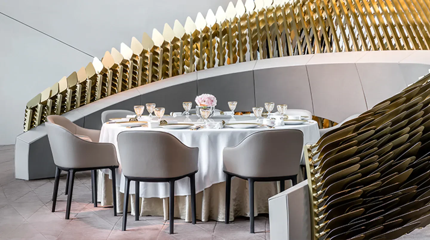 Elegant dining space at Yí restaurant in Macau, featuring modern gold accents and soft lighting.