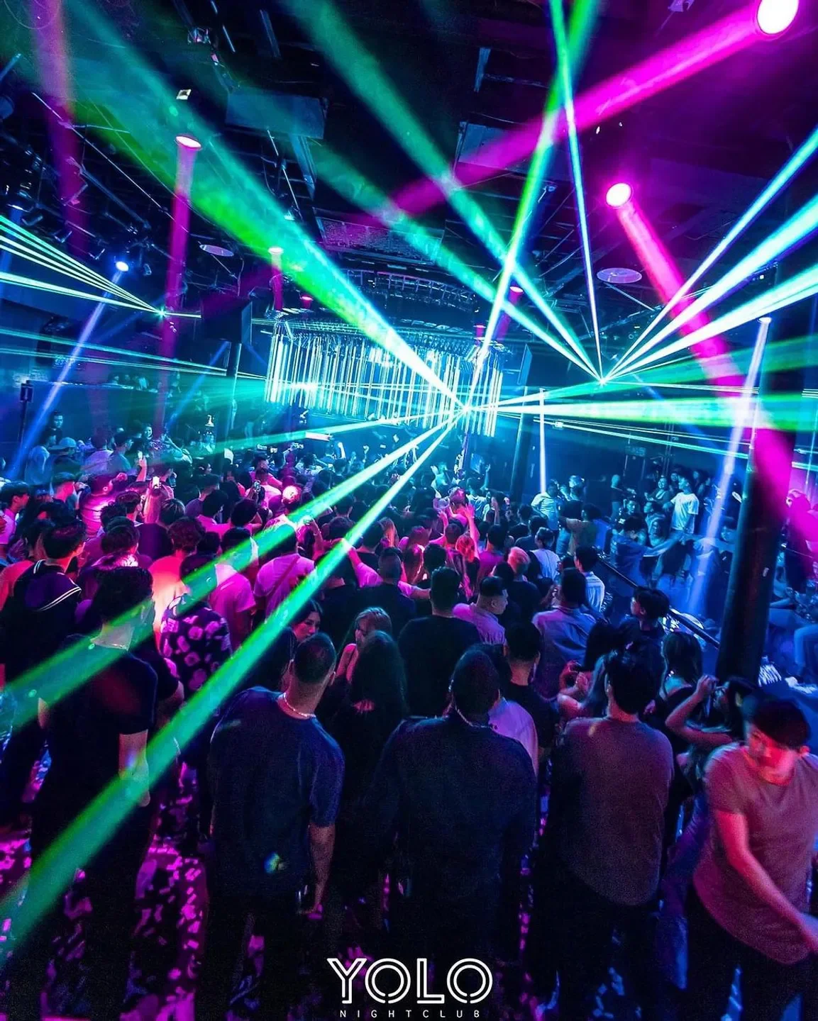 Energetic dance floor at YOLO Nightclub in San Francisco with colorful laser lights.