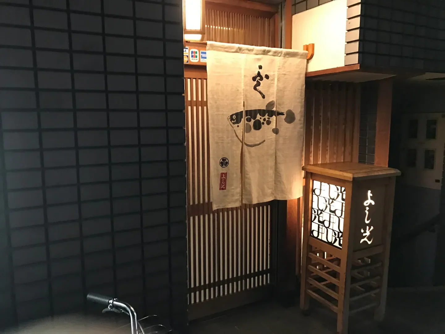 Entrance to Yoshiko restaurant in Osaka, Japan, featuring a traditional lantern and curtain.