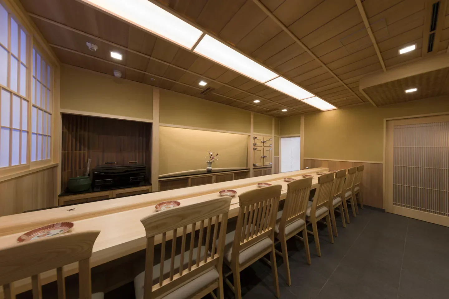 Interior of Yoshitake restaurant in Tokyo. A long wooden sushi bar with seating.