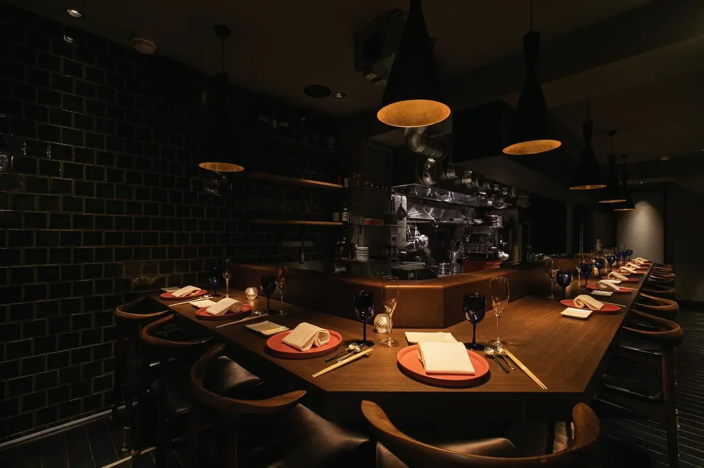 Interior of YUNiCO restaurant in Osaka, showcasing dark wood counter and dining setting.