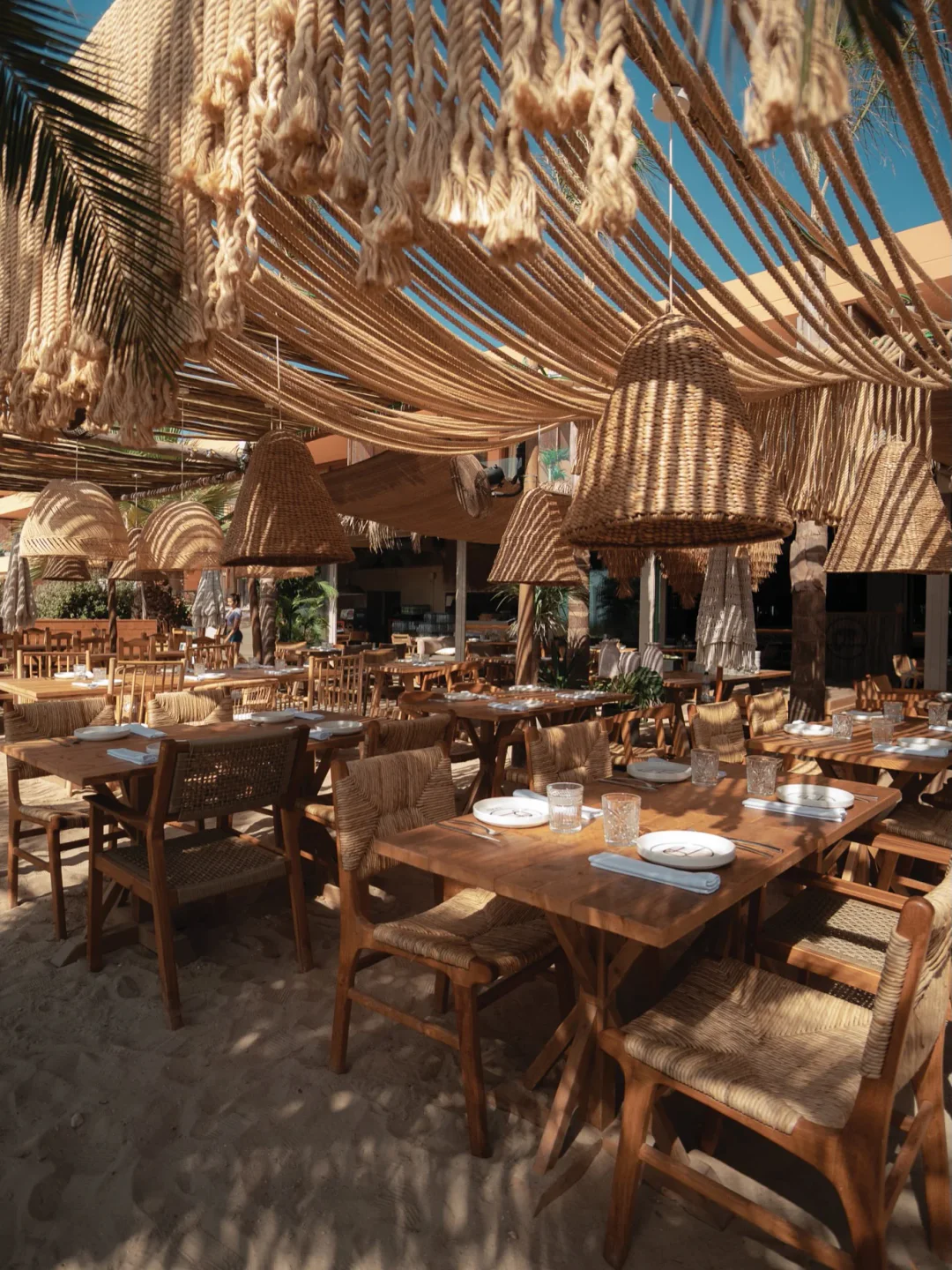 Zazu Ibiza restaurant's sandy floor and natural decor with woven lamps and beachside seating