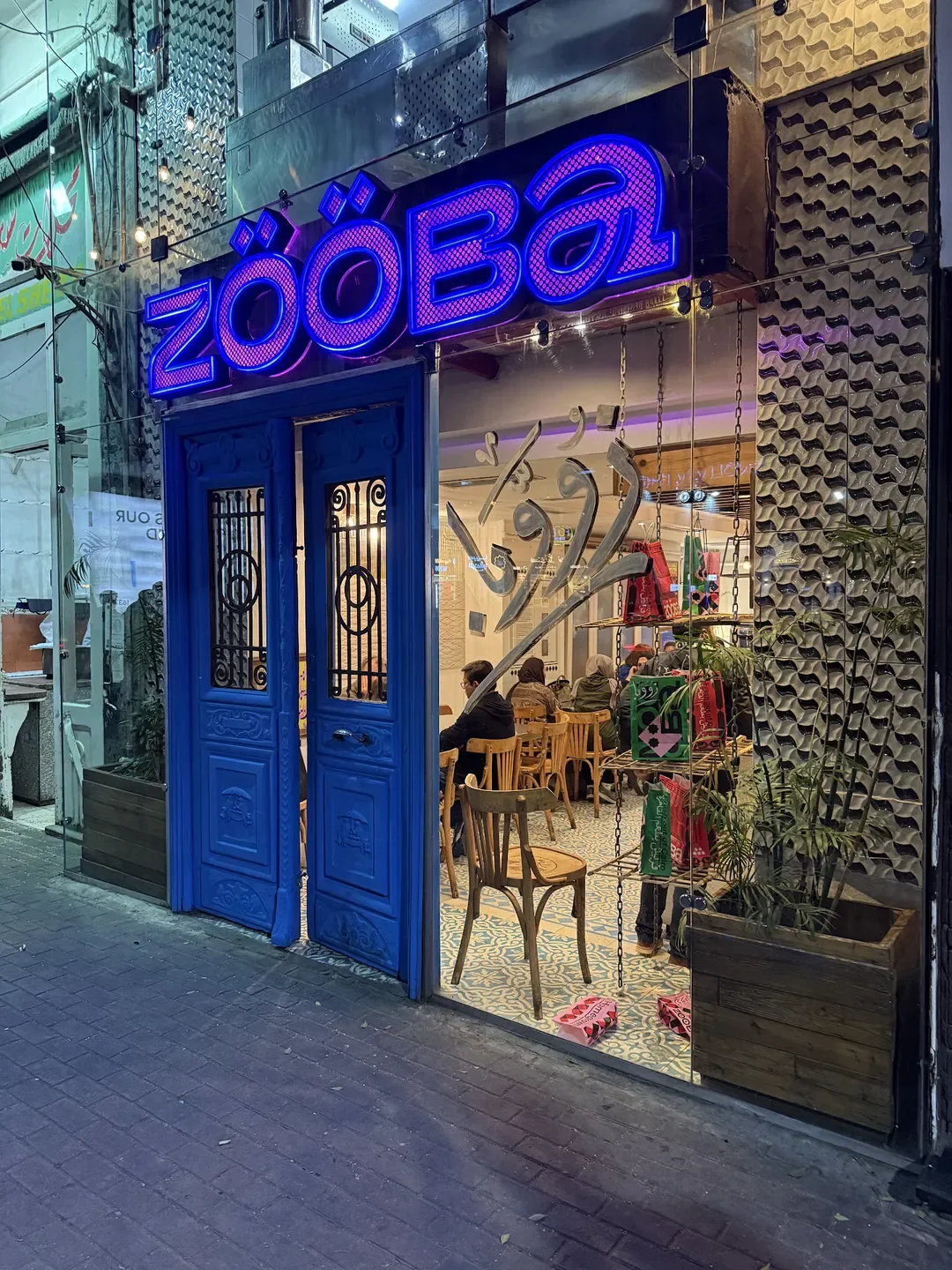 Zööba restaurant entrance in Cairo, with neon sign and blue doors, inviting patrons inside.