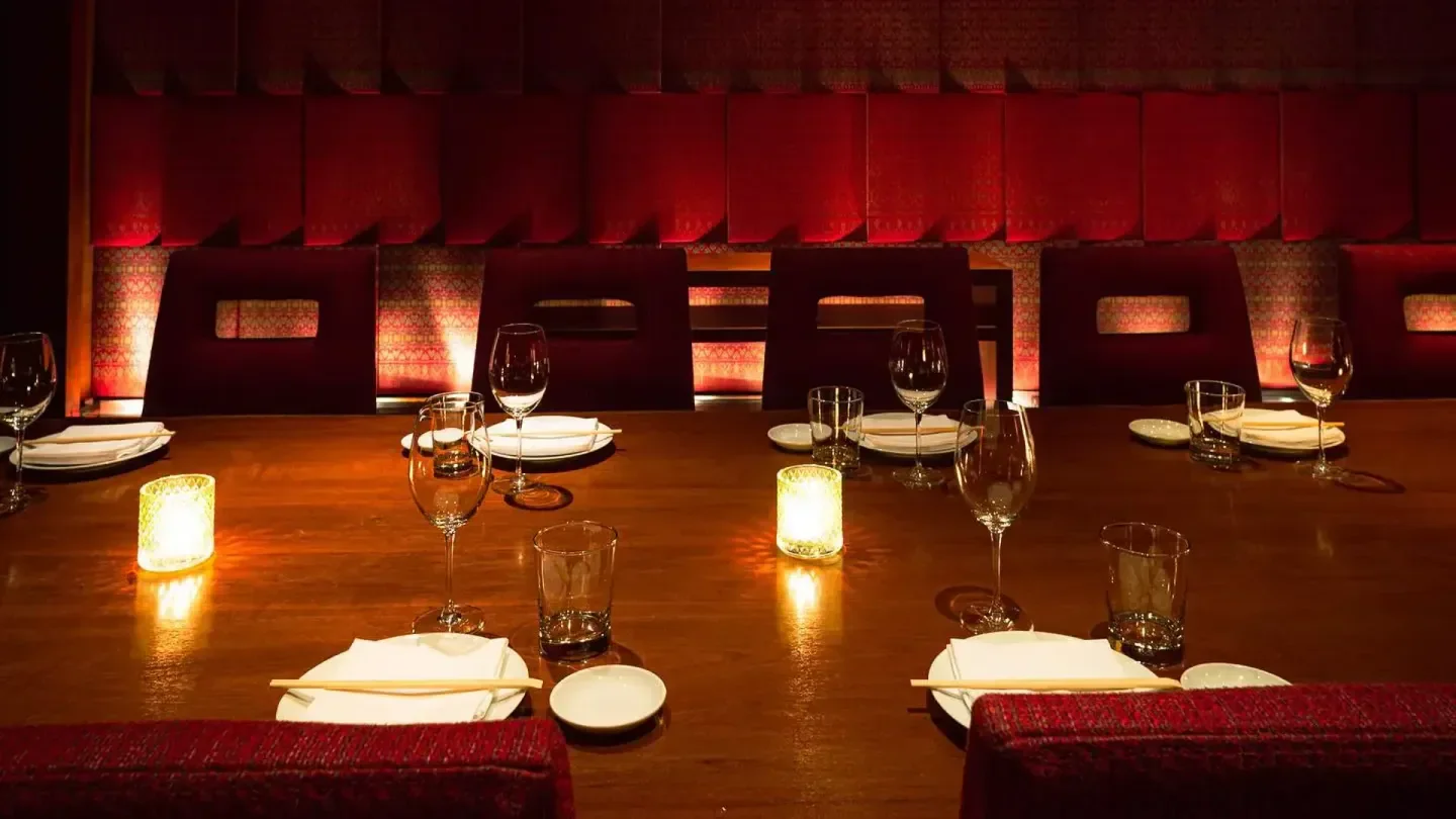 Elegant dining table setting at Zuma Bangkok restaurant, with wine glasses and candlelight.